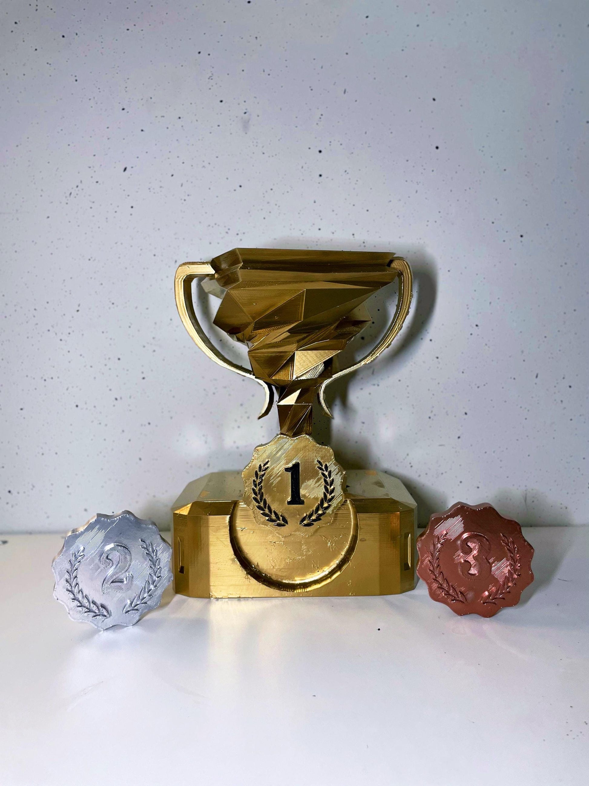 A 3D-printed trophy set featuring gold, silver, and bronze awards with a modern geometric design, perfect for competitions, events, and decorative display.